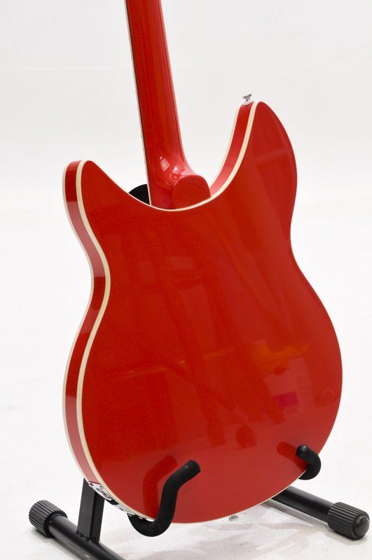 A red electric guitar is sitting on a black stand.