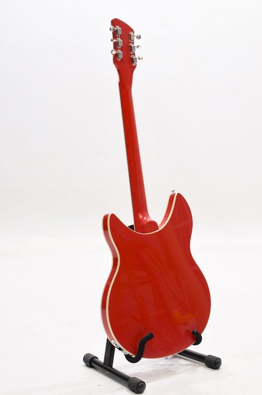 A red electric guitar is sitting on a stand on a white background.