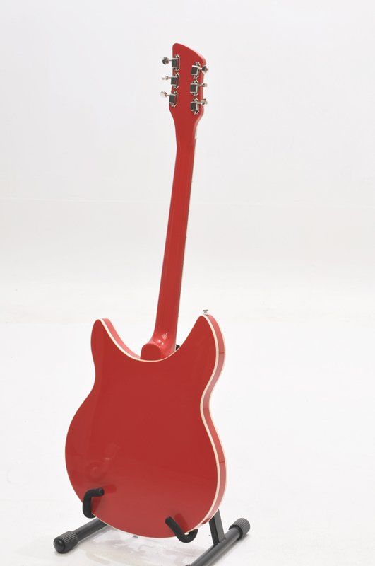 A red guitar is sitting on a stand on a white background