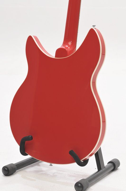 The back of a red guitar is shown on a stand