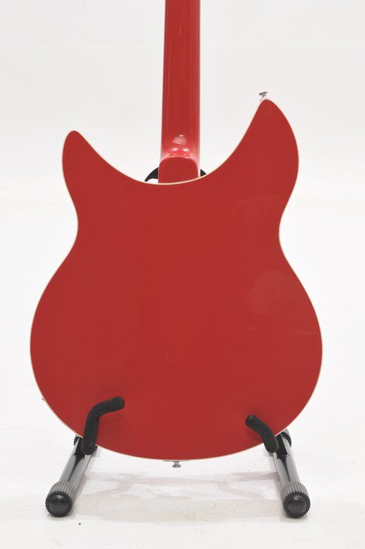 A red guitar is sitting on a stand on a white background