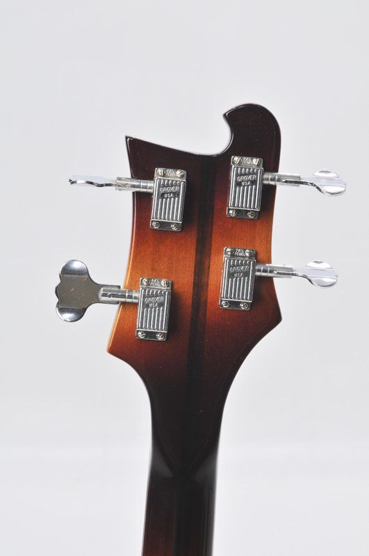 A close up of the headstock of a bass guitar on a white background.