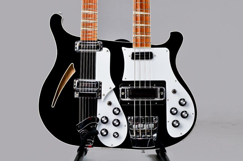 A black double neck guitar is sitting on a stand