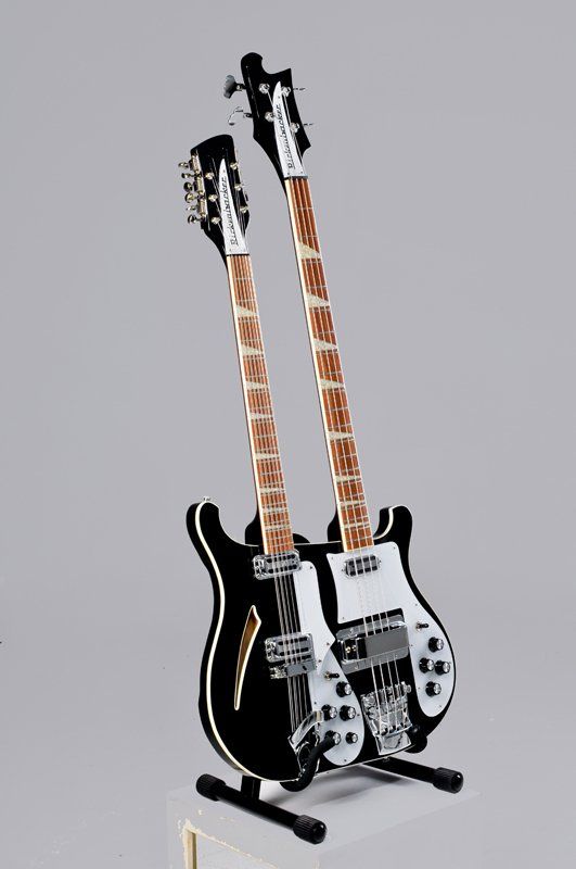 Two guitars are sitting on top of each other on a stand.