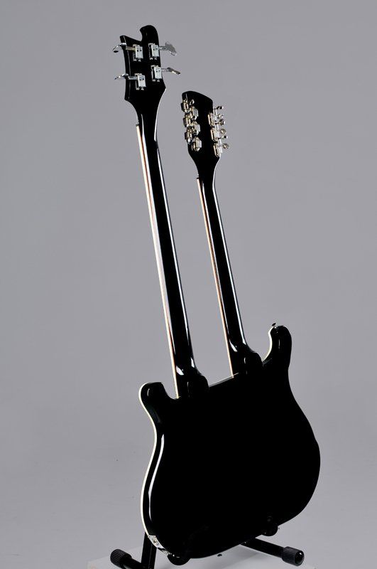 A black guitar with two necks is sitting on a stand