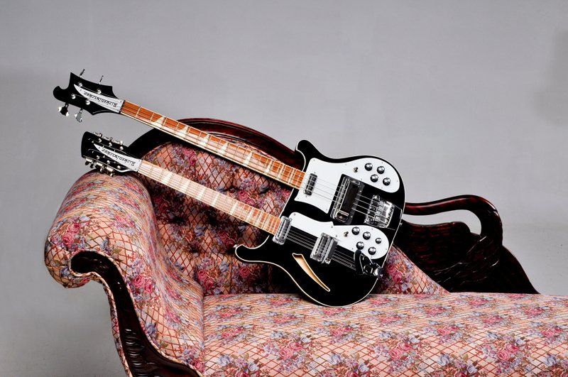 A double neck guitar is sitting on a couch.