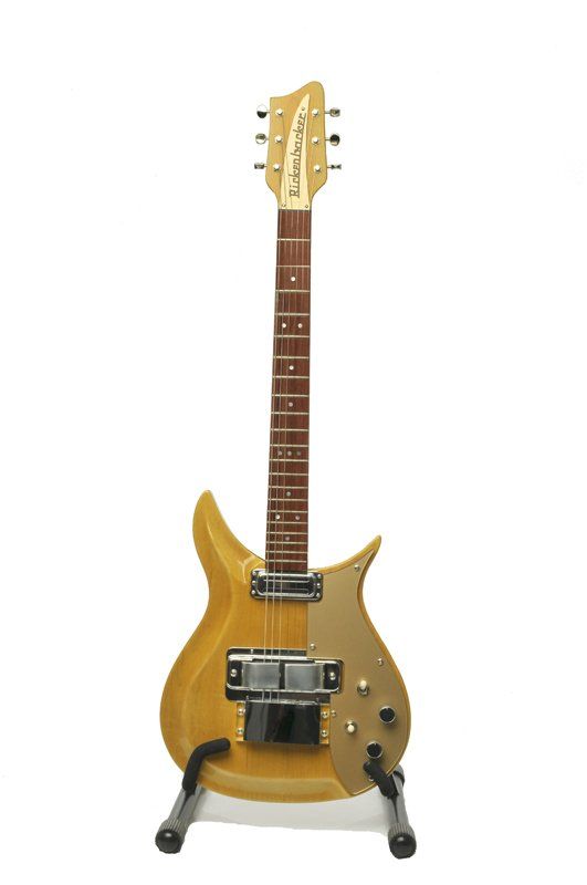 A rickenbacker guitar is sitting on a stand on a white background.