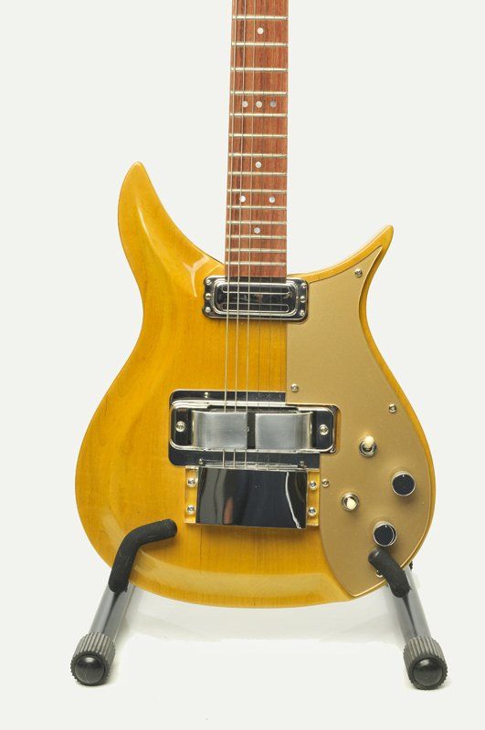 A yellow electric guitar is sitting on a stand
