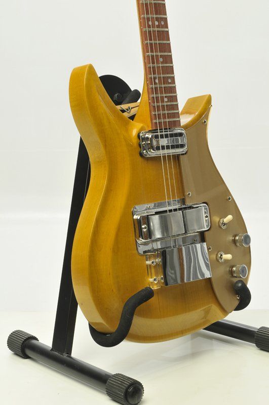 A yellow guitar is sitting on a black stand