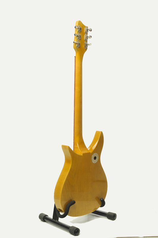 A yellow electric guitar is sitting on a stand on a white background.