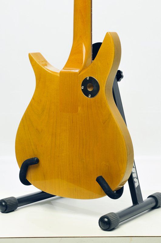 The back of a guitar is shown on a stand