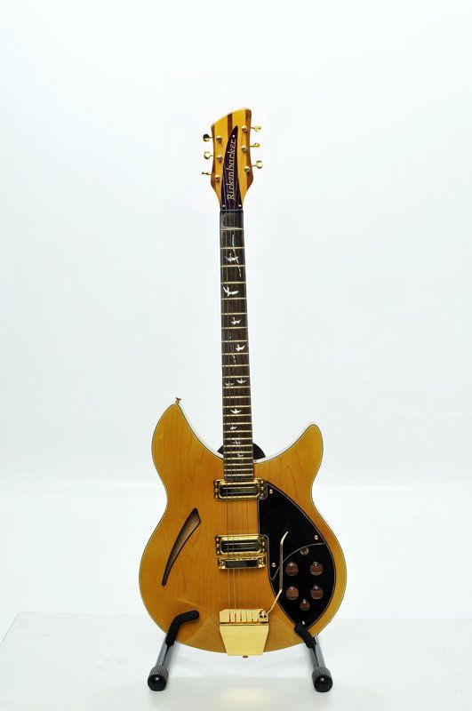 A guitar is sitting on a stand on a white surface.