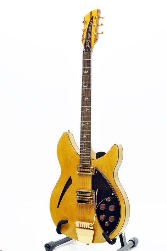 A yellow electric guitar is sitting on a stand on a white background.