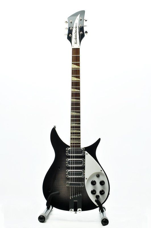 A black and white electric guitar is sitting on a stand on a white background.