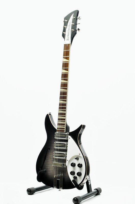 A black electric guitar is sitting on a stand on a white background.