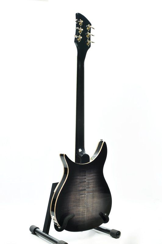A black electric guitar is sitting on a stand on a white background.