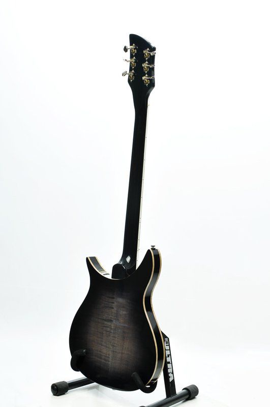 A black electric guitar is sitting on a stand on a white background.