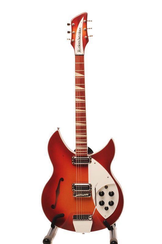 A red and white guitar is sitting on a stand on a white background.