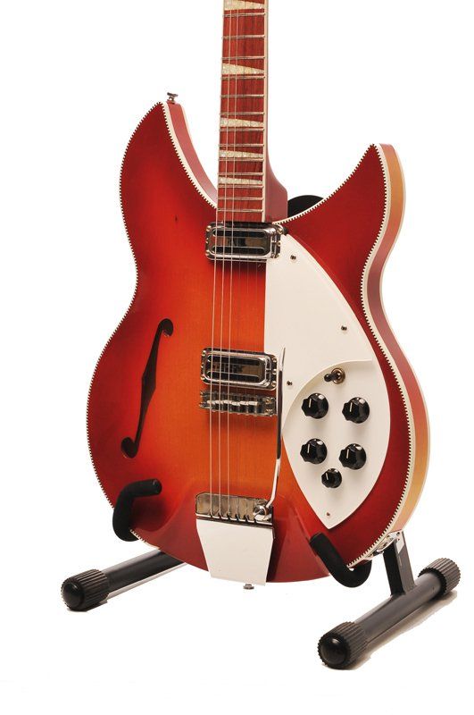 A red and white guitar is sitting on a stand