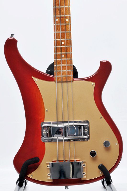A red and tan bass guitar is sitting on a stand