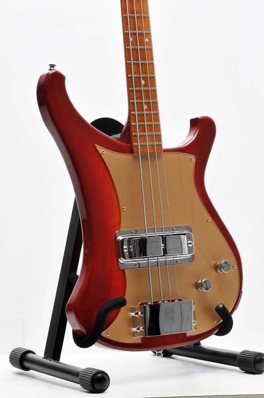 A red and gold bass guitar is sitting on a stand