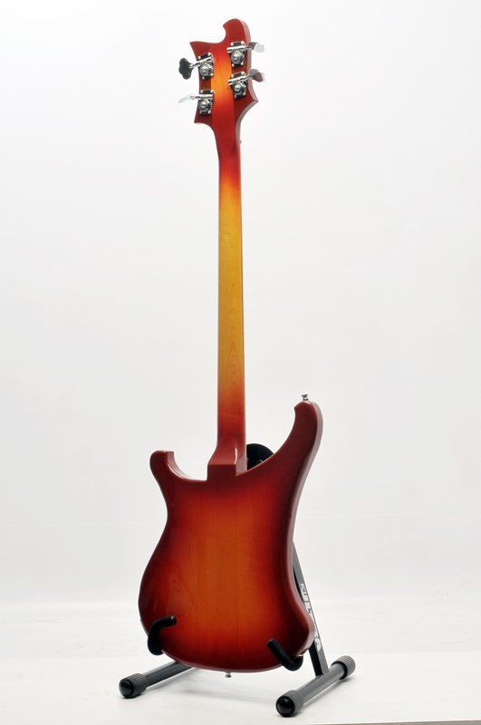 A red electric guitar is sitting on a stand on a white background.