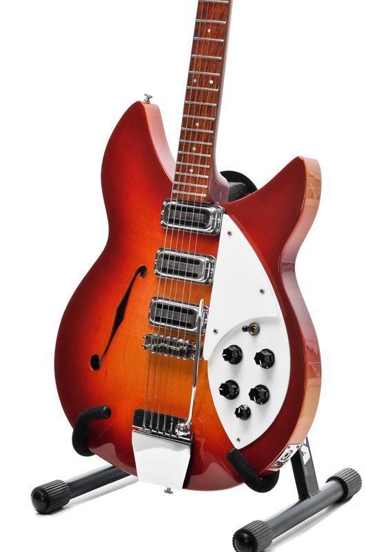 A red guitar is sitting on a stand on a white background