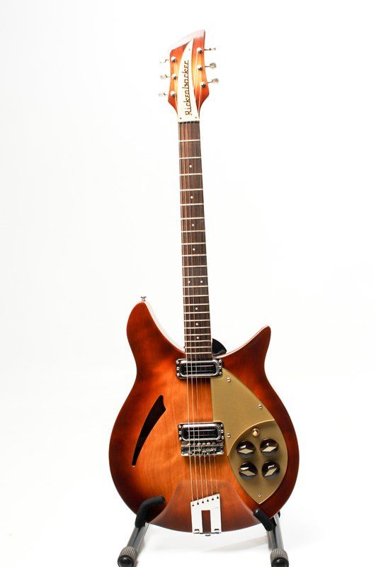 A brown electric guitar is sitting on a stand on a white background.