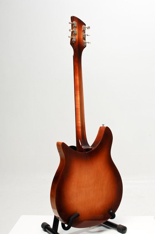 A brown electric guitar is sitting on a stand on a white surface.