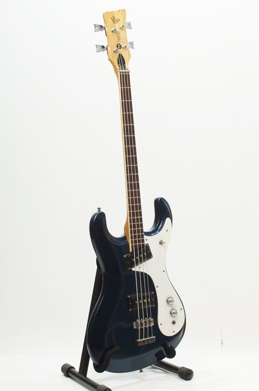 A black electric bass guitar is sitting on a stand