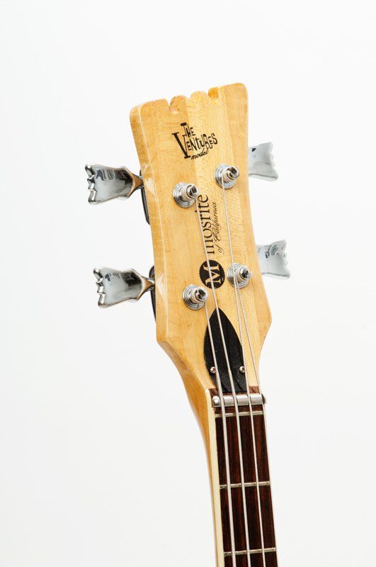 A close up of the headstock of a bass guitar on a white background.