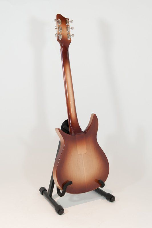 A guitar is sitting on a stand on a white surface.
