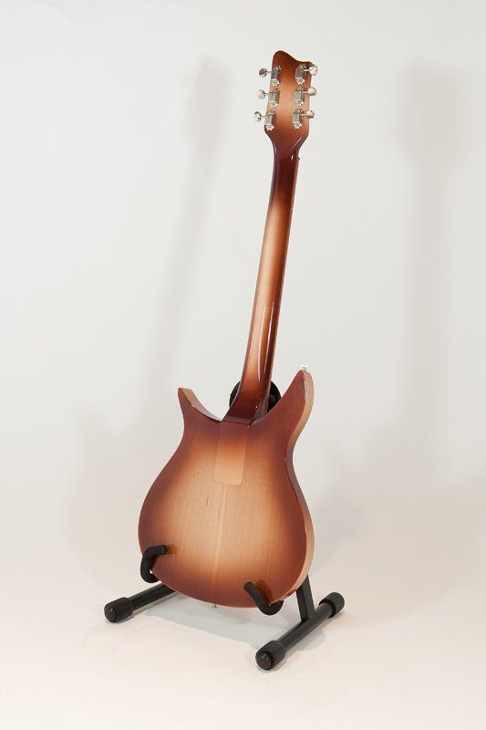 A guitar is sitting on a stand on a white surface.