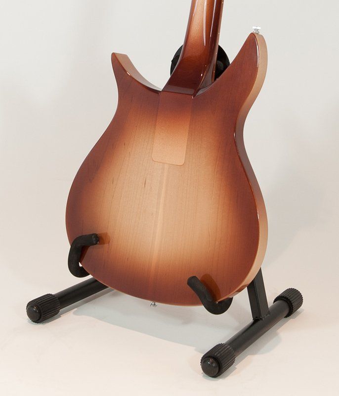 A brown guitar is sitting on a black stand