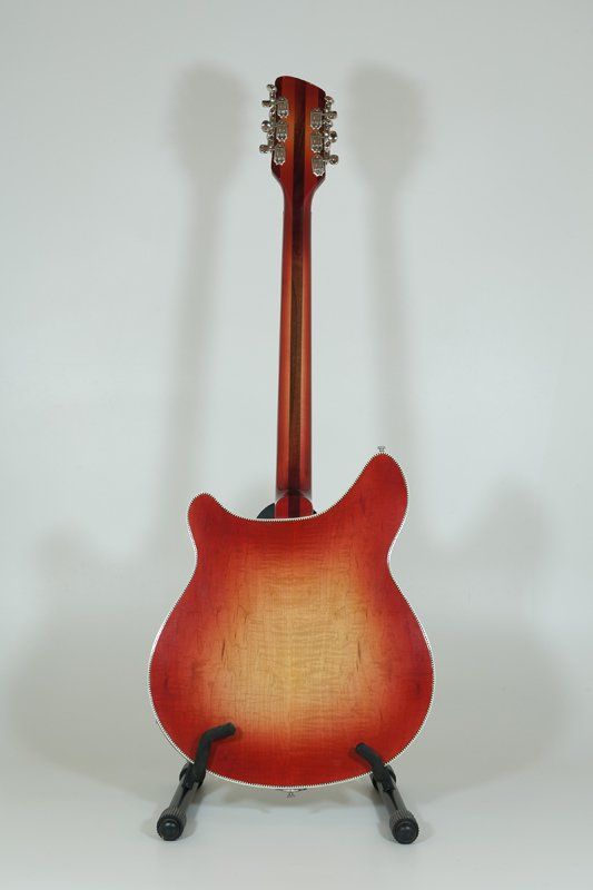 A red electric guitar is sitting on a stand on a white surface.