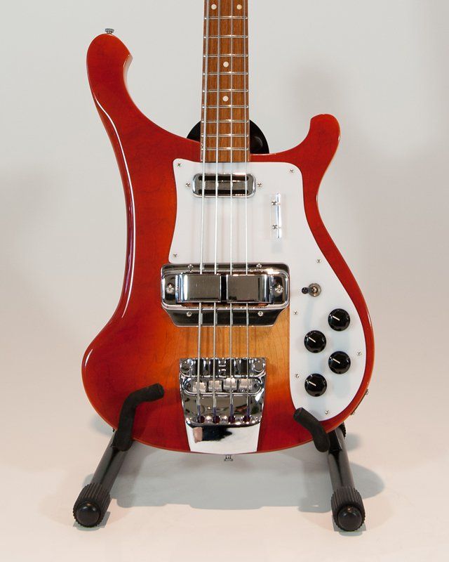 A red bass guitar is sitting on a stand
