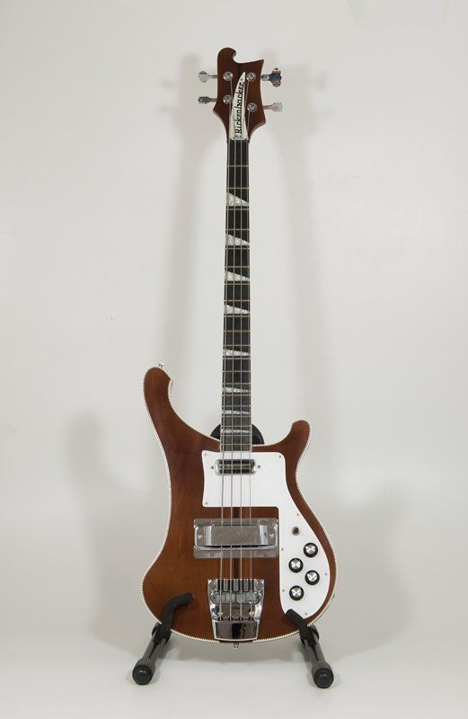 A brown and white electric bass guitar is sitting on a stand.