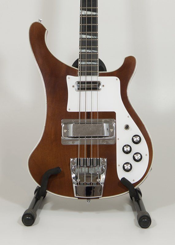 A brown and white bass guitar is sitting on a stand