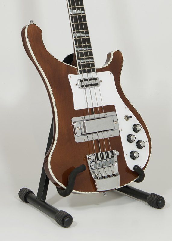 A brown and white bass guitar is sitting on a stand
