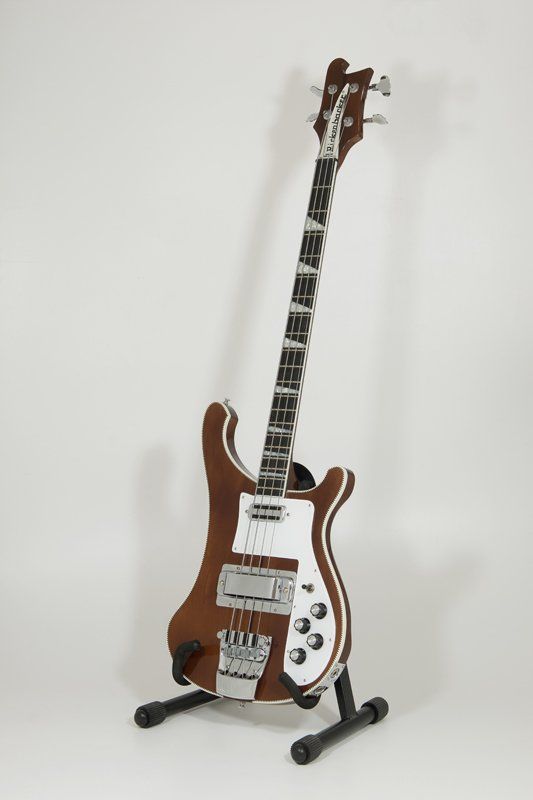 A brown and white electric guitar is sitting on a stand.