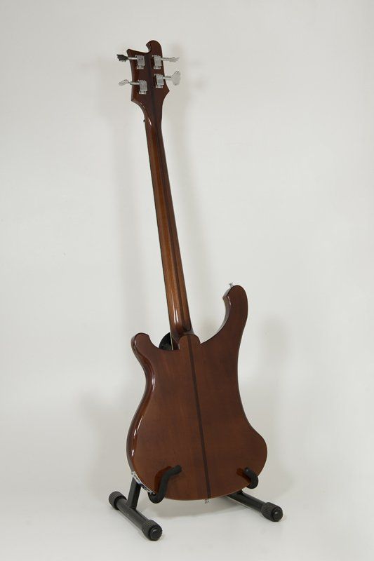 The back of a bass guitar is shown on a stand