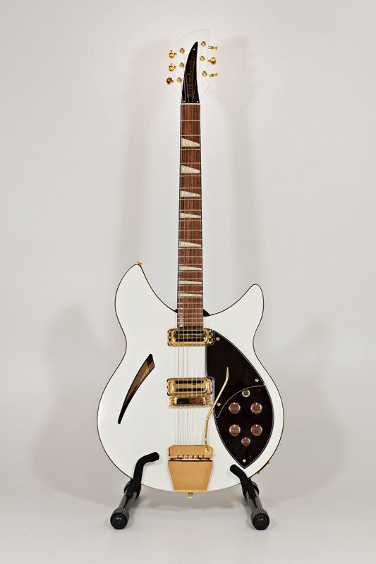 A white electric guitar is sitting on a stand.