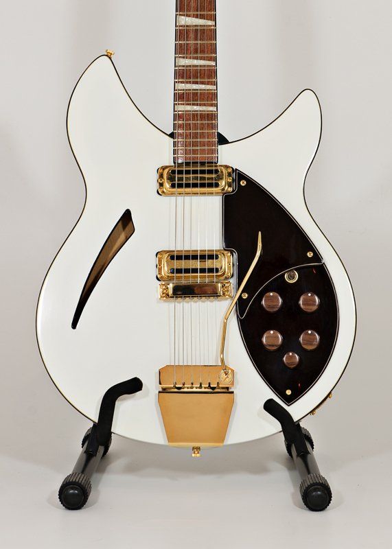 A white electric guitar is sitting on a stand