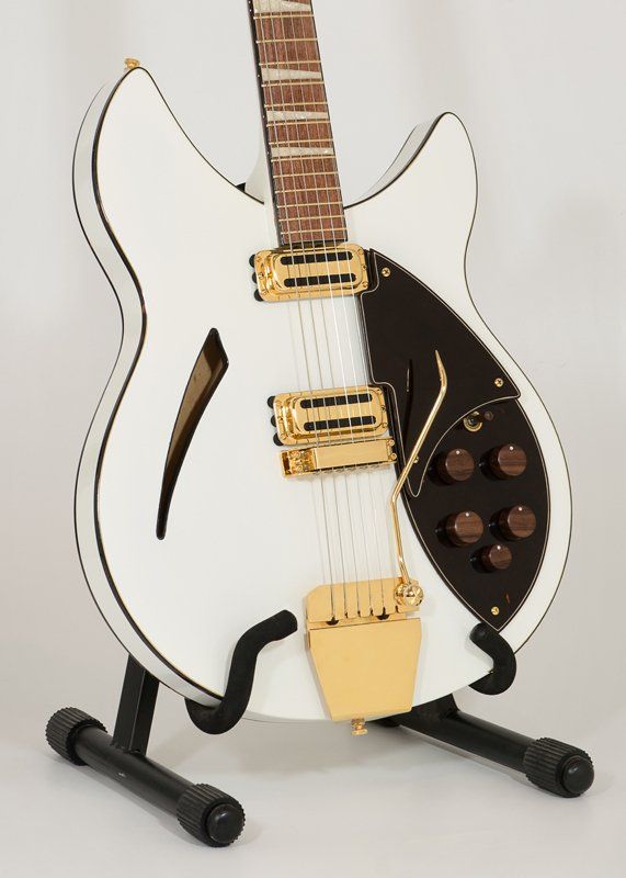 A white guitar is sitting on a black stand