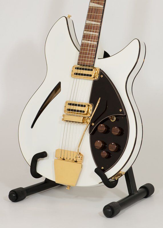 A white guitar is sitting on a black stand