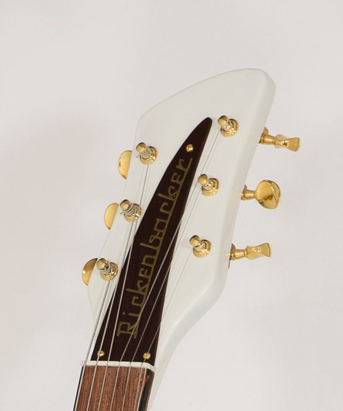 A white rickenbacker guitar headstock with gold knobs