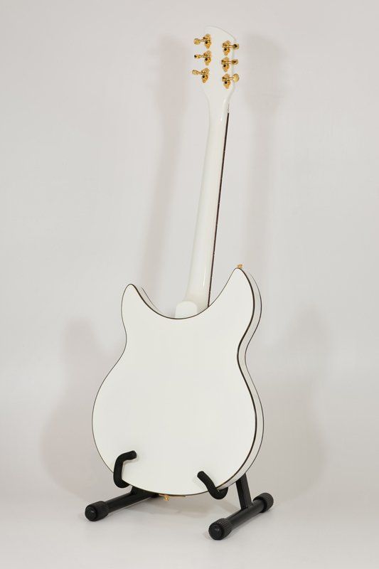 A white electric guitar is sitting on a black stand.