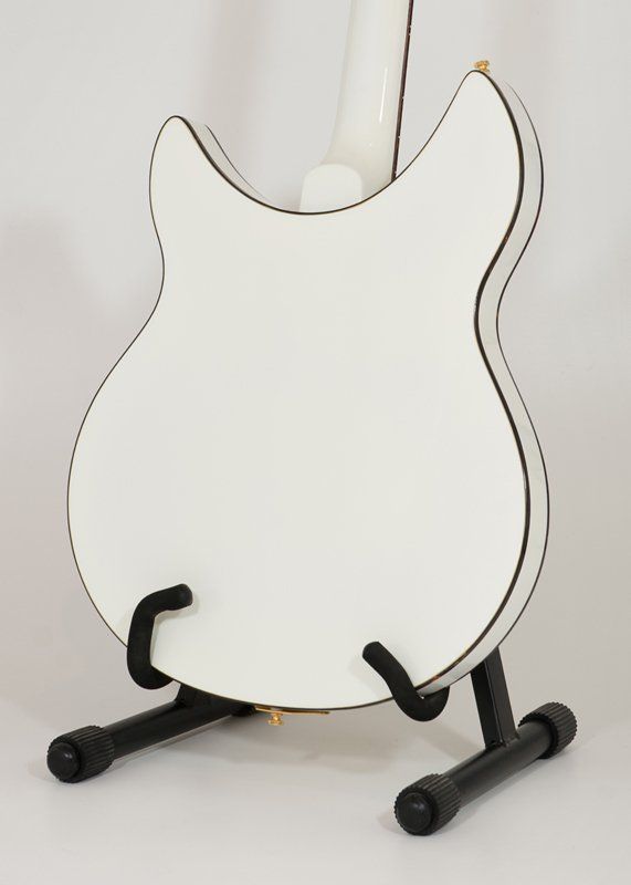A white guitar is sitting on a black stand