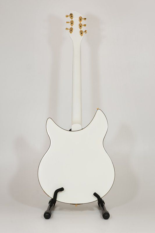 A white guitar is sitting on a stand on a white surface.