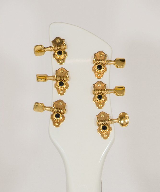 The headstock of a white guitar with gold tuners